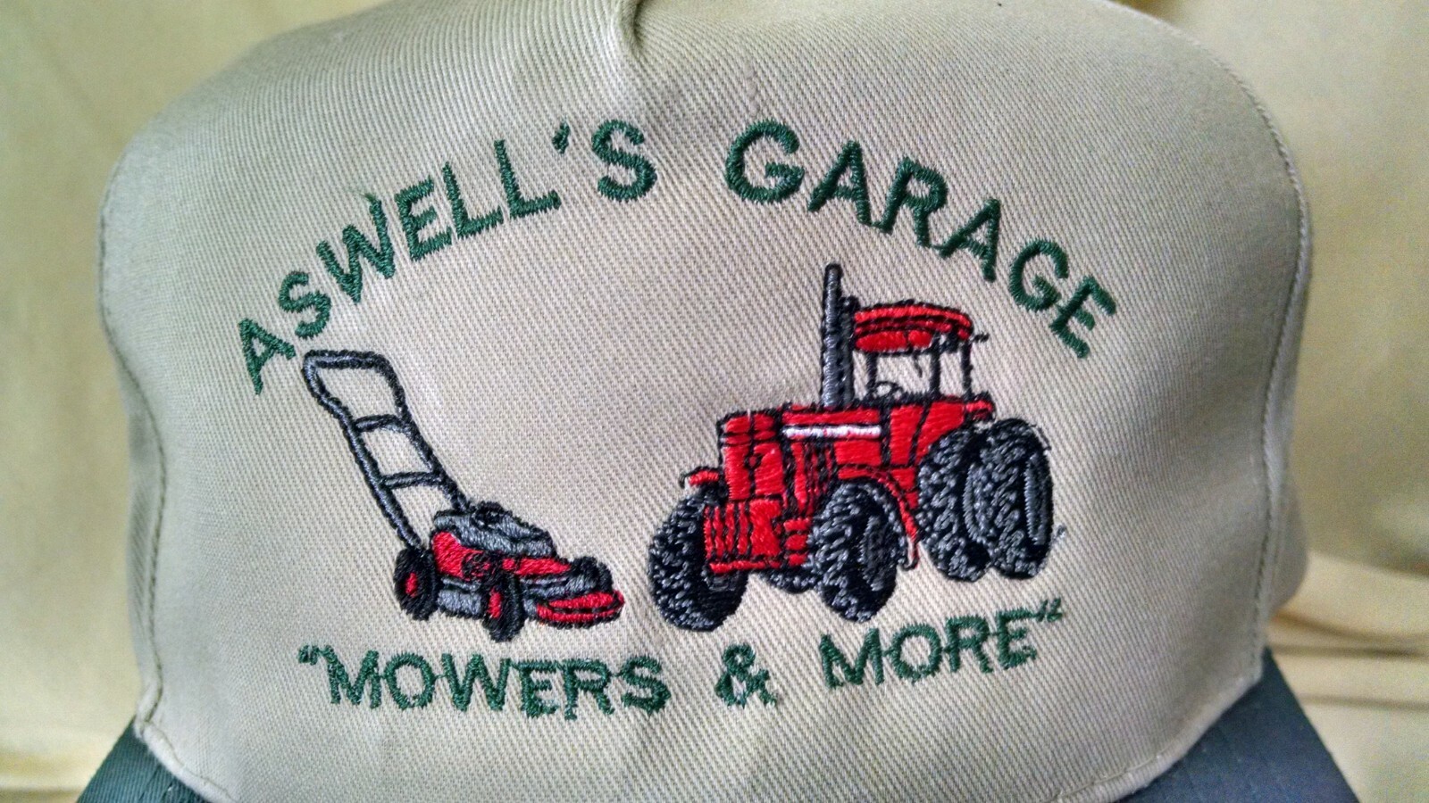 ASWELL’S GARAGE HAT MOWERS & MORE GRASS CUTTER TRACTOR BEIGE GREEN OTTO ADJBL.